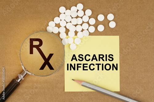 On the table are pills, a magnifying glass, pencils and a sticker with the inscription - Ascaris Infection photo