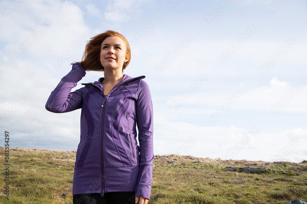 Redhead woman outside in countryside wearing purple workout jacket Redhead woman outside in countryside wearing purple workout jacket