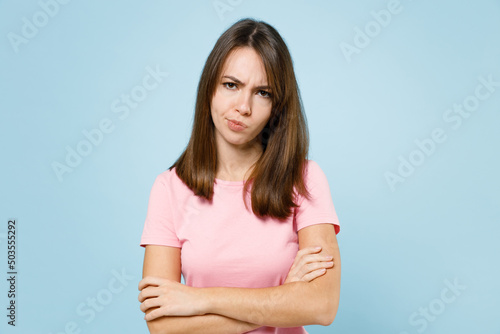 Papier peint Young sad disappointed displeased caucasian woman 20s wear pink t-shirt look camera hold hands crossed folded isolated on pastel plain light blue background studio portrait