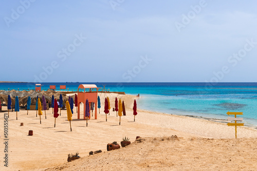 Red sea coastline with public beach club and colorful sun tents. Seascape in Egypt.