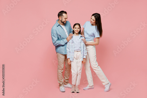 Full body young happy caucasian smiling fun parents mom dad with child kid daughter teen girl in blue clothes look camera hug cuddle isolated on plain pastel light pink background. Family day concept.