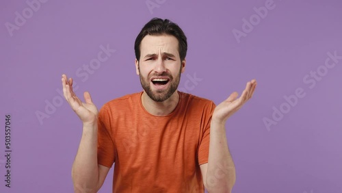 Distempered unnerved sad young brunet bearded man 20s years old wears red t-shirt looking up asking why raising spreading shaking hands isolated on plain pastel light purple background studio portrait photo