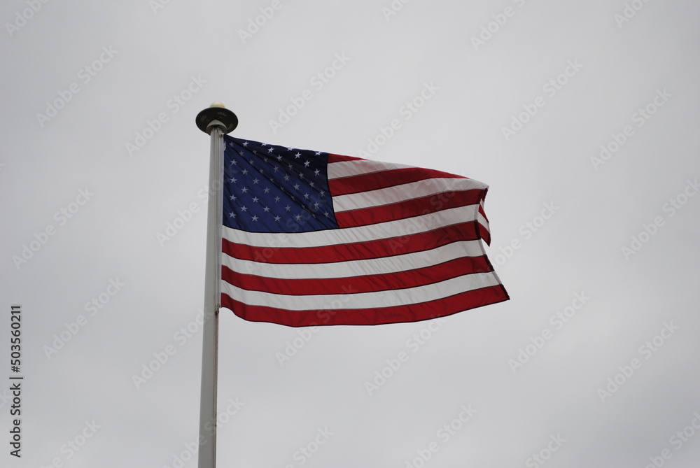 American flag blowing in the wind against a gray sky American flag blowing in the wind against a gray sky