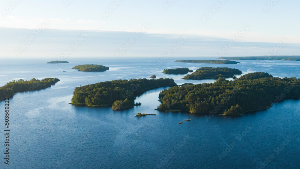 Small rocky islands with a forest in the middle of a large lake in summer at dawn aerial view