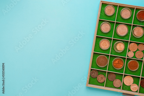 Numismatics coin collection album with copy space. Top view of old rare coins on blue background