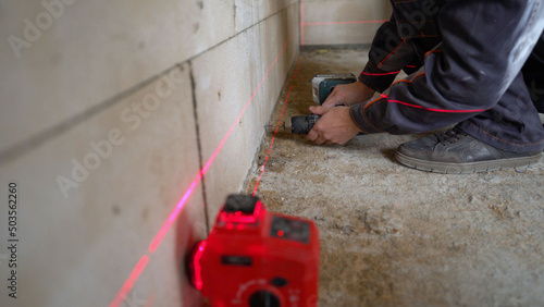 A worker is drilling a wall. Installation of metal rails on the wall. Workers are drilling the wall. Construction worker installing metal rails on clamps on a block wall. Wall repair process.