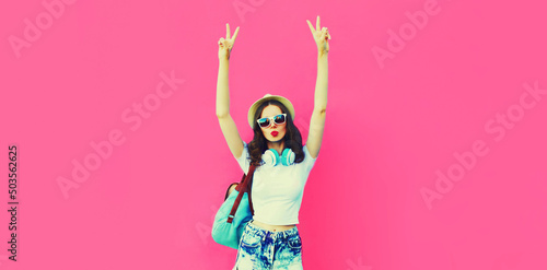 Summer colorful portrait of stylish modern young woman having fun listening to music in headphones posing on pink background, blank copy space for advertising text