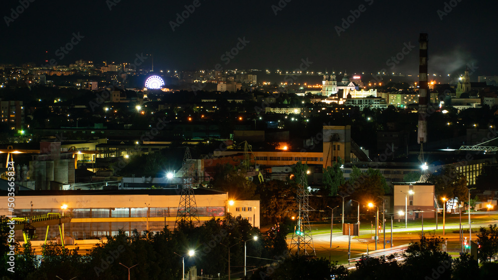 Fototapeta premium Night panorama of the city. Tall apartment buildings illuminated by night illumination. Top view of windows and roofs of houses