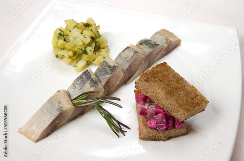 Appetizing pieces of herring laid out on a white plate with garnish photo