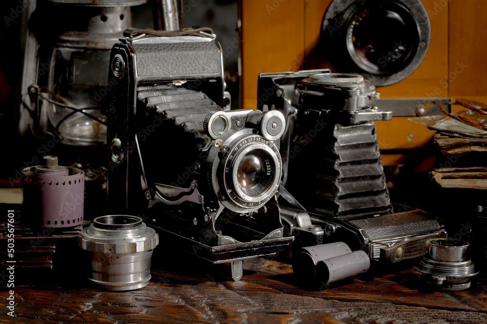 Fototapeta premium An old camera in a composition on an old background, on a table