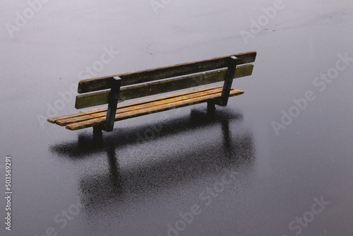 Single wooden bench in the middle of nowhere with rain pouring down on it