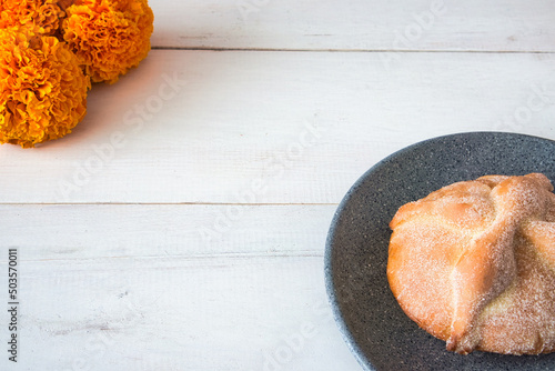 Closeup of baked sweet bread on a black plate with orange marigold flower decorations photo