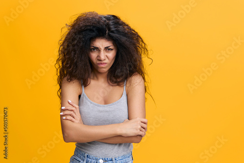 Canvas Mad pretty Latin female with afro cross hands, angry look to camera, have problems, offended by boyfriend, stay isolated over yellow background