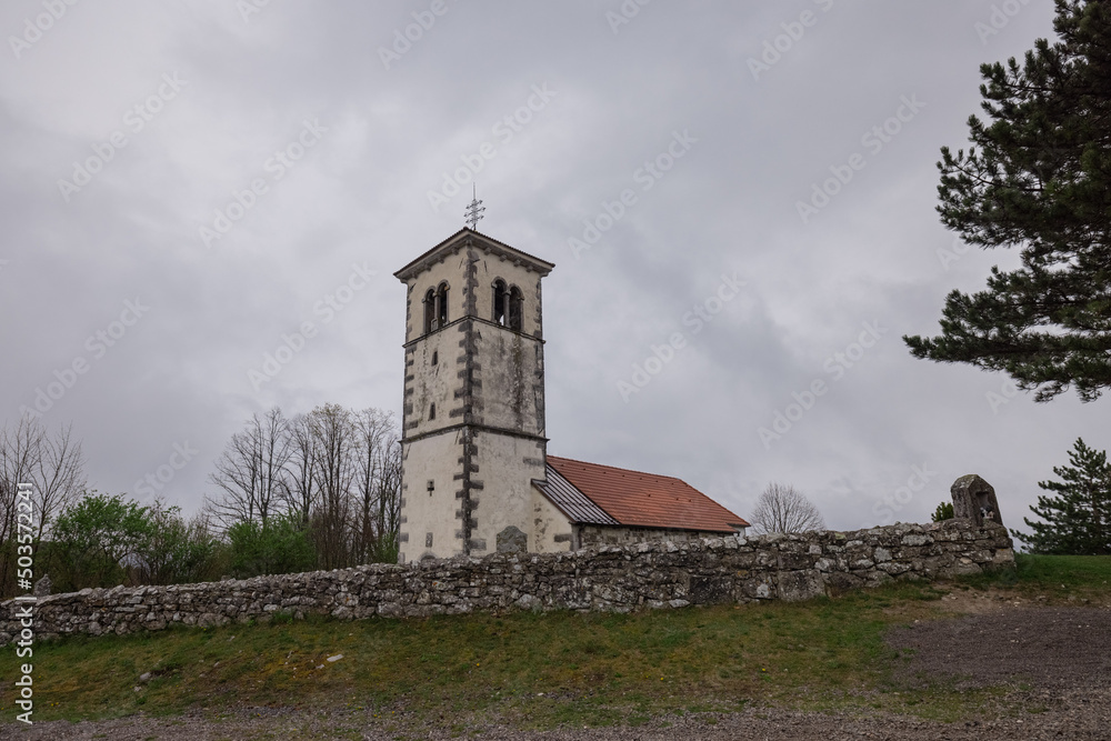 Fototapeta premium Church in silentabor, a small hill above Pivka, Slovenia on a cloudy rainy day. Istrian style church on a top of a hill.