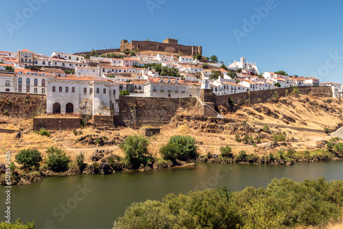View of the village of Mértola in Portugal, with the Guadiana river in the foreground, on a sunny day in summer. photo
