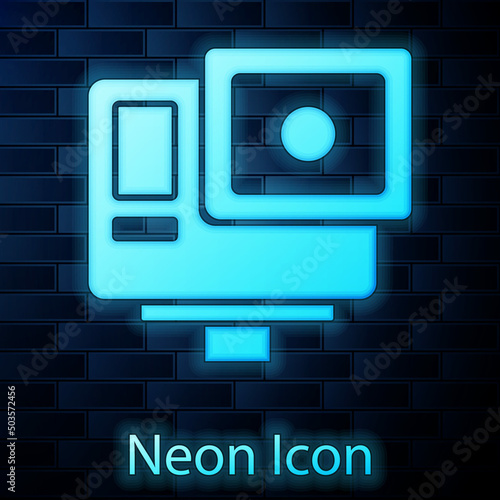 Glowing neon Action extreme camera icon isolated on brick wall background. Video camera equipment for filming extreme sports. Vector