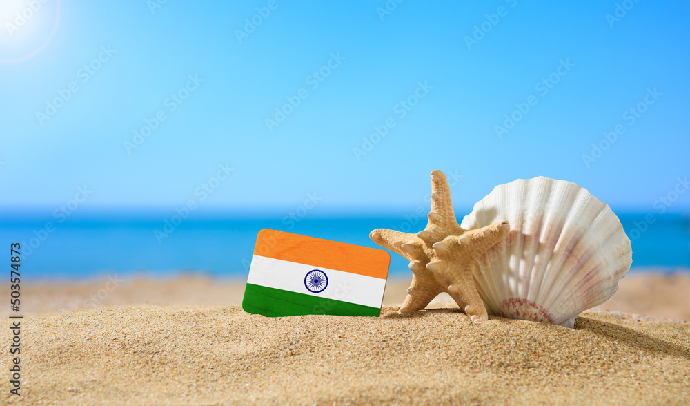 Tropical beach with seashells and India flag. The concept of a paradise vacation on the beaches of India. - obrazy, fototapety, plakaty 