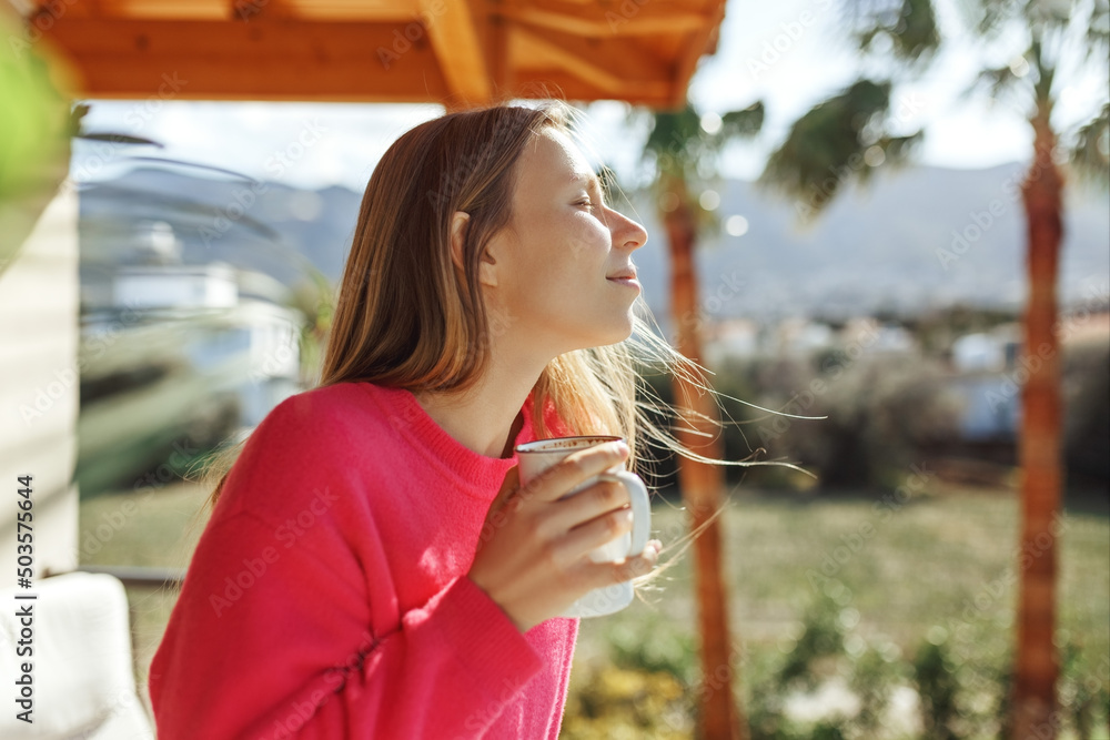Fototapeta premium Young woman enjoying the view from apartment,drinking morning coffee on the balcony.