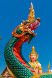 Vertical shot of the Buddhist Naga and Buddha statues against blue sky in bright sunlight