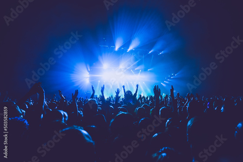 Fototapeta A crowded concert hall with scene stage lights in blue tones, rock show performa