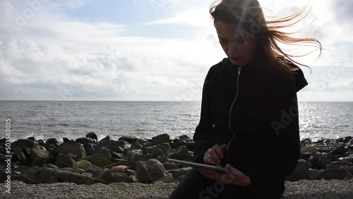 girl sitting in a tablet with the sea as her backdrop. High quality FullHD footage