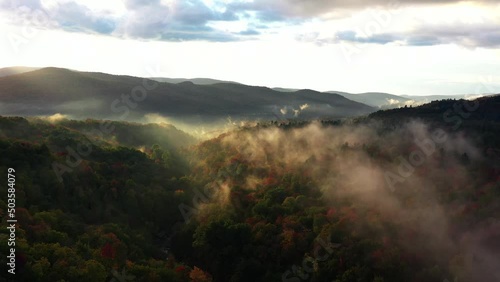 Aerial drone footage of a beautiful sunrise over New England, during Golden Hour.  With fog rising above the trees.