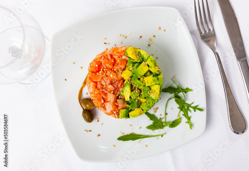 Foto Delicious seafood tartare made of raw salmon, onion and avocado served with arug