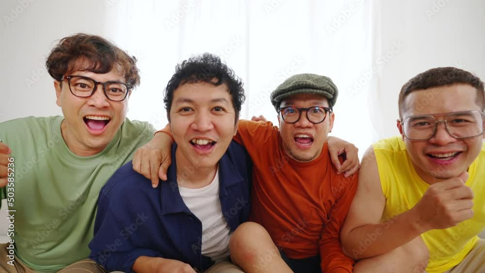 Group of Asian man friends sitting on sofa watching soccer game competition on television with drinking beer together at home. Happy male soccer fans cheering victory football team victory sport match Group of Asian man friends sitting on sofa watching soccer game competition on television with drinking beer together at home. Happy male soccer fans cheering victory football team victory sport match