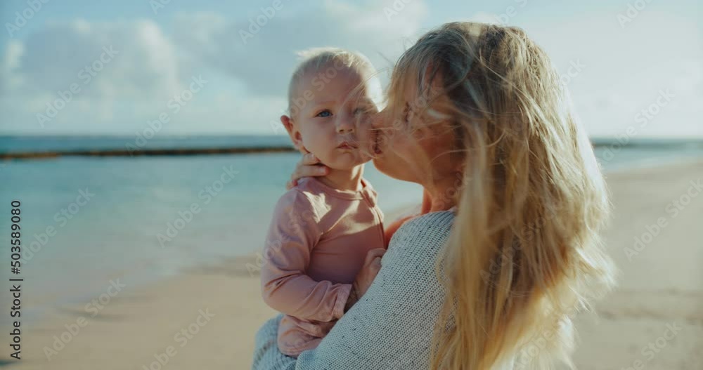 Beautiful mother and cute young baby on the beach at sunrise, family lifestyle