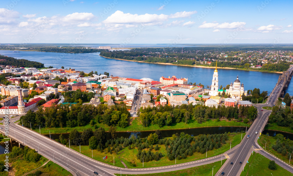Scenic summer view from drone of historic center of Rybinsk city located on banks of Volga with bridge and ancient Transfiguration Cathedral with golden spire of bell tower, Russia