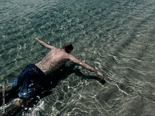 A man floats on the surface of the water, face down. Drowned in the ocean. Soft focus
