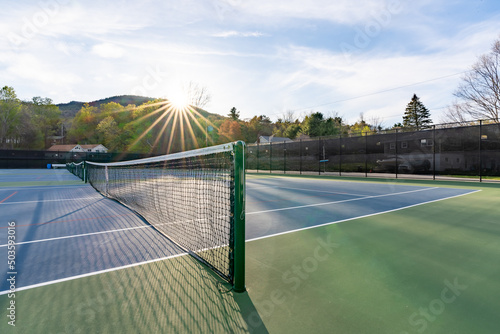 Fotografie New blue outdoor tennis courts with white lines and red pickleball lines and background sun star