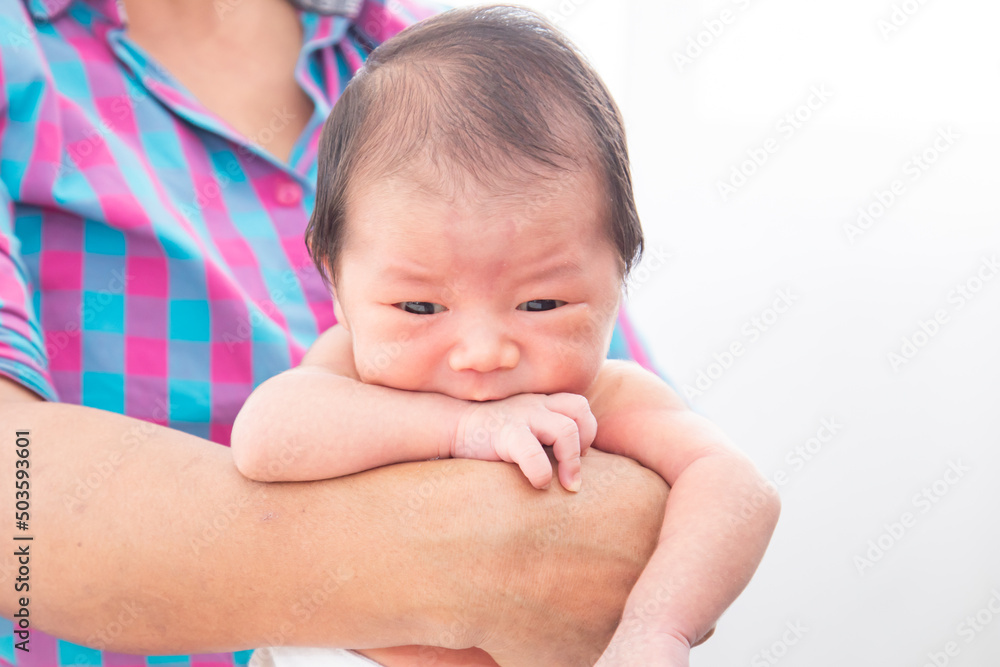 Close up of Asian little newborn baby in her mother's arms, expressing warm loving caring feeling. Cute adorable baby hungry after wake up. Mom holding infant with safe and care. Close up of Asian little newborn baby in her mother's arms, expressing warm loving caring feeling. Cute adorable baby hungry after wake up. Mom holding infant with safe and care.