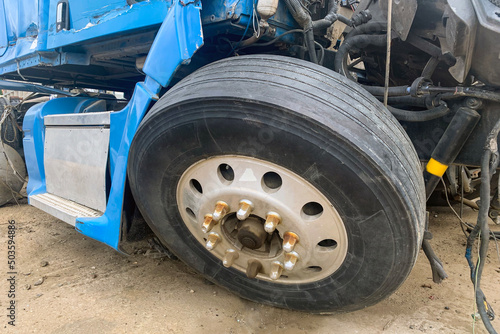 Closeup of abandoned truck in a junkyard, a blue lorry with a destroyed wheel and other parts after an accident on the road, big broken automobile on a junk yard.