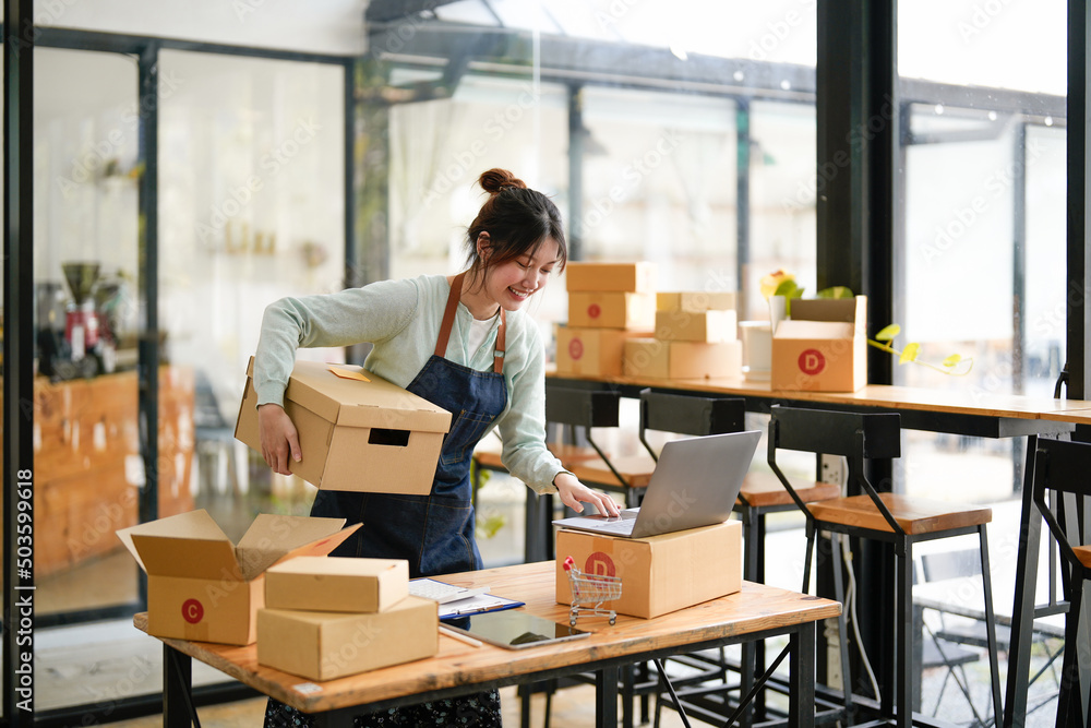 Startup small business SME, Entrepreneur owner using laptop computer taking receive and checking online purchase shopping order to preparing pack product box. Selling online ideas concept Startup small business SME, Entrepreneur owner using laptop computer taking receive and checking online purchase shopping order to preparing pack product box. Selling online ideas concept