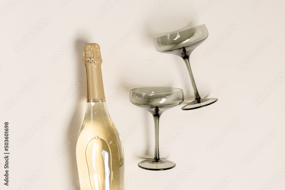 Champagne or sparkling wine bottle, champagne glasses from tinted grey glass  on beige background. Festive drink minimal concept. Modern wine glasses,  dark colored glass. Creative top view, flat lay Stock 写真