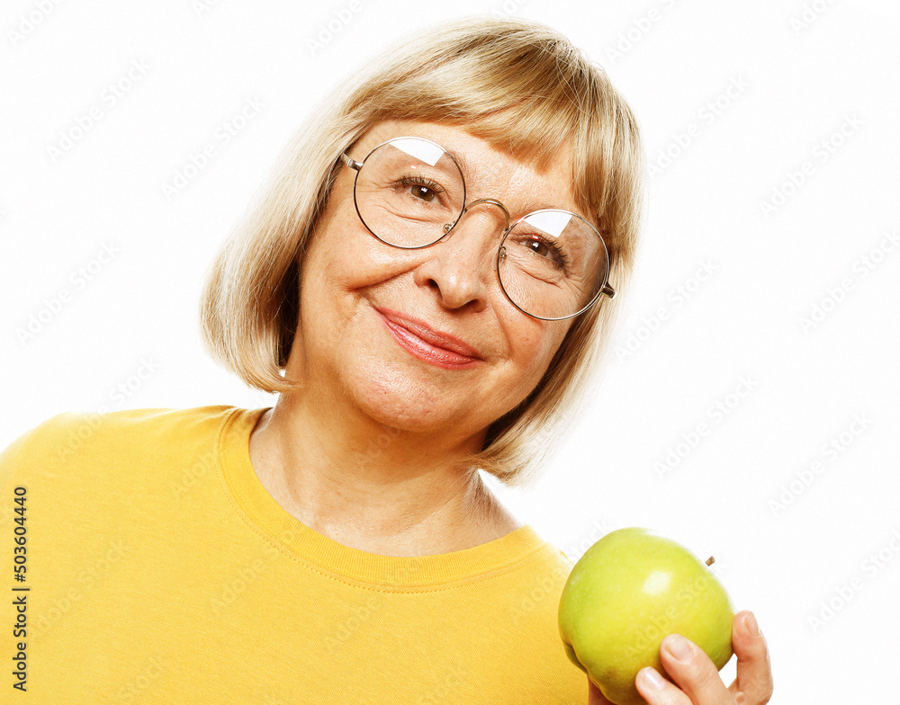 Food, health and old people concept: Portrait of senior woman holding an apple by her mouth Food, health and old people concept: Portrait of senior woman holding an apple by her mouth
