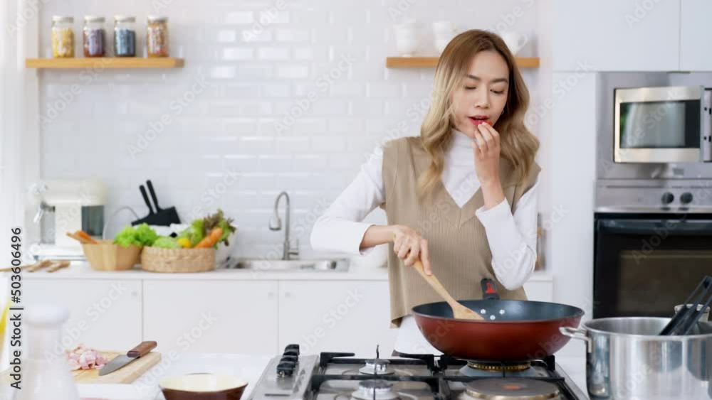 Beautiful Asian woman enjoy cooking healthy food pasta and salmon steak on cooking pan in the kitchen at home. Happy female having dinner party meeting celebration with friends on holiday vacation Beautiful Asian woman enjoy cooking healthy food pasta and salmon steak on cooking pan in the kitchen at home. Happy female having dinner party meeting celebration with friends on holiday vacation