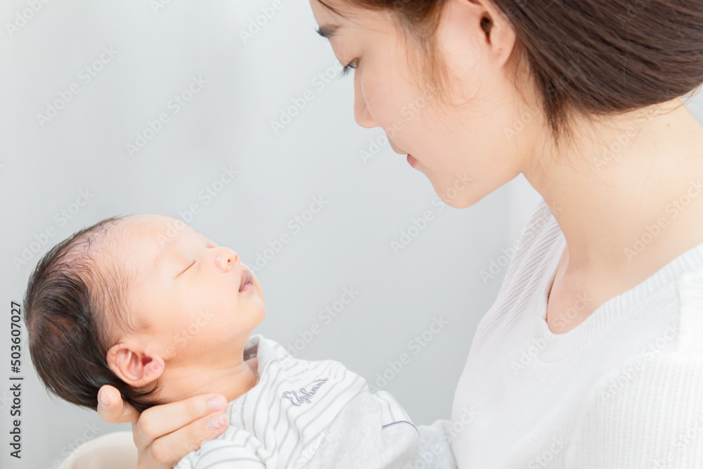 Asian mother holding her newborn in arm, young woman looking her first son with love and care, baby in mom arm sleeping with happy and safe, infant and mother concept. Asian mother holding her newborn in arm, young woman looking her first son with love and care, baby in mom arm sleeping with happy and safe, infant and mother concept.