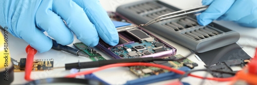 Εκτύπωση καμβά Foreman in rubber gloves repairing mobile phone with tweezers in workshop closeu