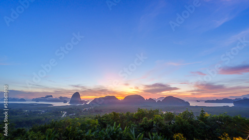 Atmosphere sunrise in the morning, sky is changing colors, there is a faded fog, the view of Phang Nga Bay is in front of a mangrove forest with mountains.
