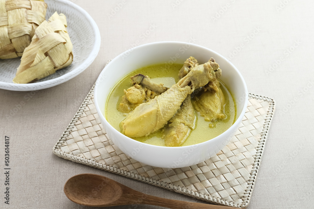 Opor Ayam with Ketupat, Indonesian traditional food. Opor made from chicken cooked with coconut milk and spices. Its served to celebrate Eid Adha and Eid Fitr. Selective focus.
