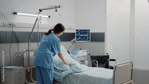 Fotografia Medical assistant preparing hospital ward bed for patient at facility