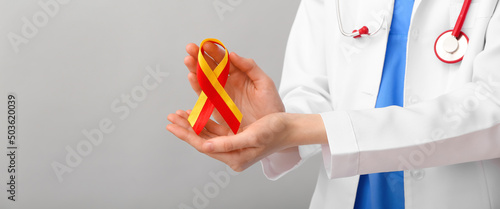 Fotografie Female doctor with awareness ribbon on grey background with space for text, closeup