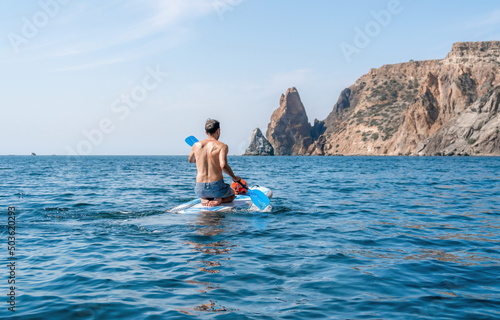 Side view foto of a man swiming and relaxing on the sup board. Sportive man in the sea on the Stand Up Paddle Board SUP. The concept of an active and healthy life in harmony with nature. © panophotograph