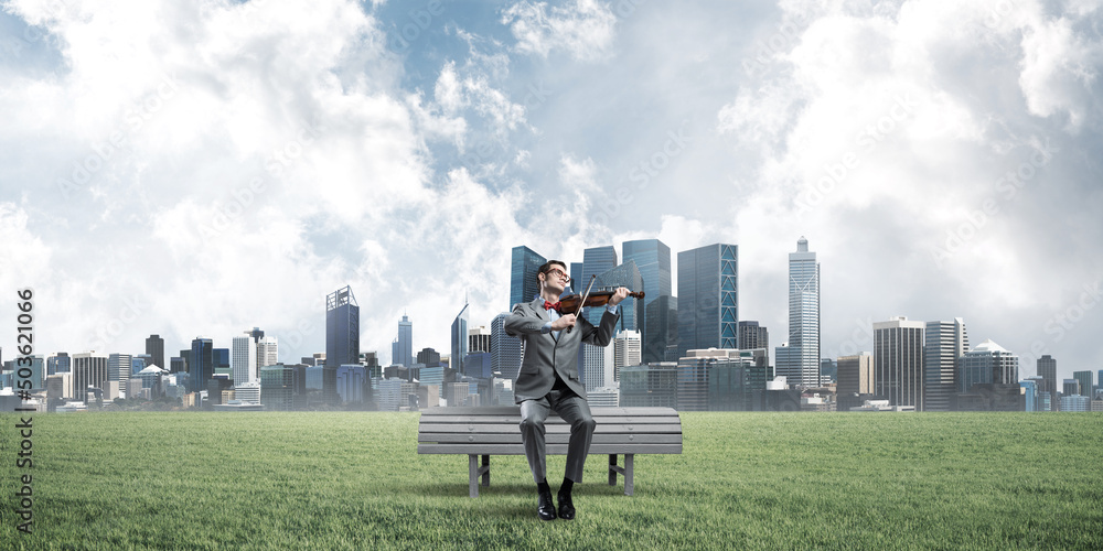 Handsome businessman in park on wooden bench play his melody Handsome businessman in park on wooden bench play his melody