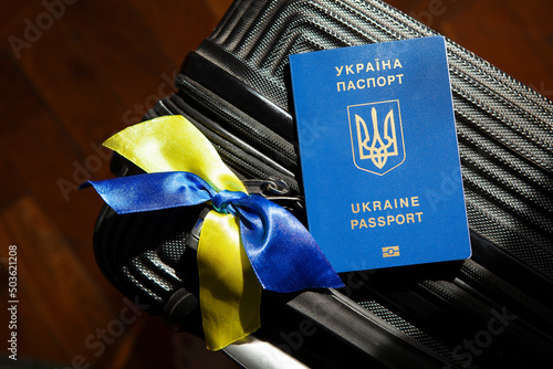 Ukrainian passport ID on luggage, yellow-blue flag ribbons. Emigration, immigration, refugee, evacuation of civilians, families from Ukraine crossing border. Stop war, support, care concept