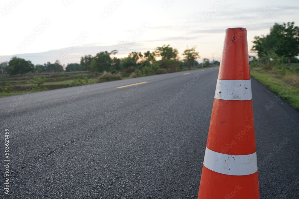 Red rubber cones are placed in the paved road.