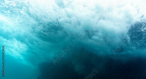 Underwater photo of a beautiful landscape and waves from below in rays of light. From a scuba dive in the wild sea.