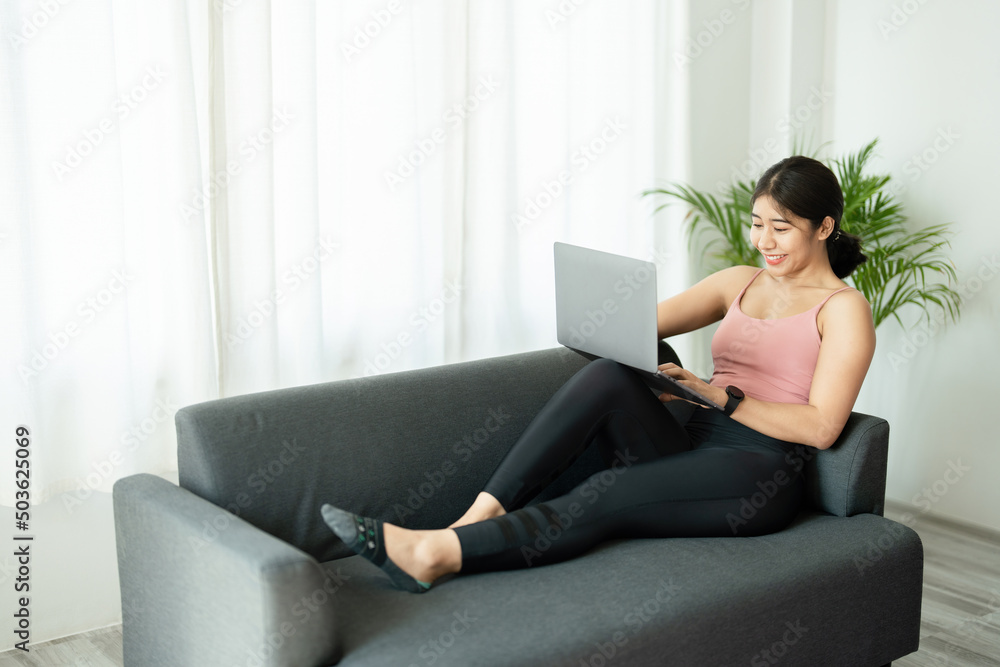 Naklejka premium stress relief, muscle relaxation, breathing exercises, exercise, meditation, portrait of Young Asian woman relaxing her body from office work by practicing yoga by watching online tutorials.